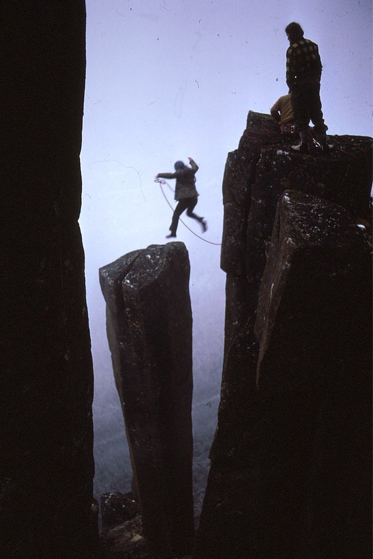 En klttrare hoppar till Albert's Tomb, en av stenpelarna p Mount Wellington.