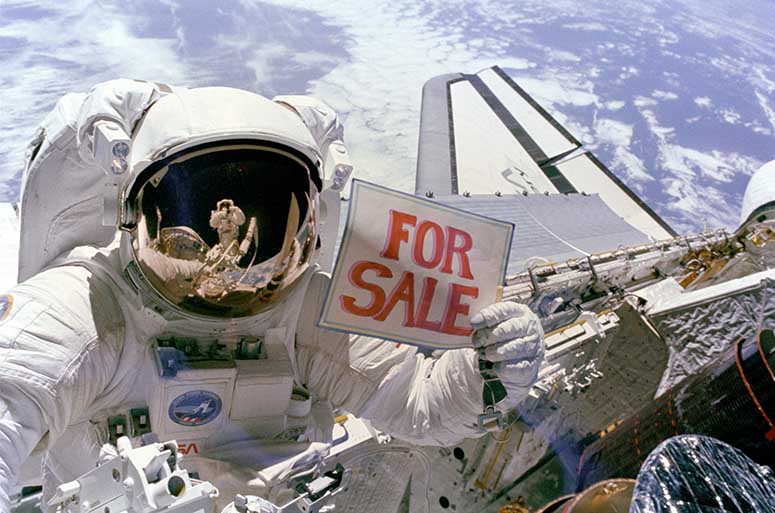 Astronaut Dale A. Gardner hller upp en skylt som det str For Sale p, i rymden.